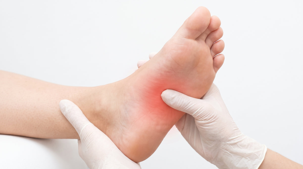 Doctor in gloves examining foot with red-highlighted heel pain area — plantar fasciitis shoe inserts