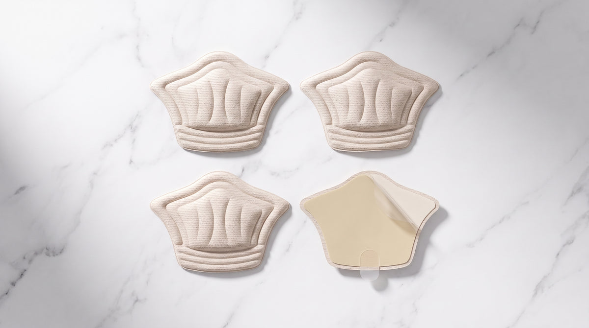 Four beige heel grip pads on marble surface, one showing adhesive backing — heel grip pads overview