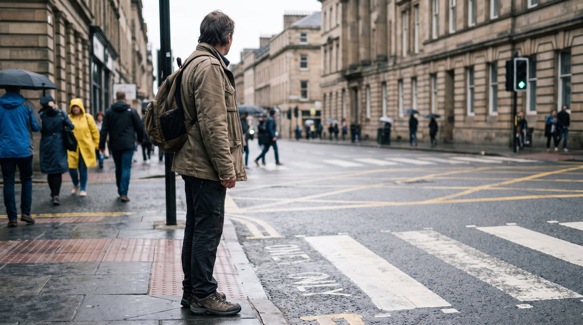 Person in walking shoes waiting at a city crosswalk
