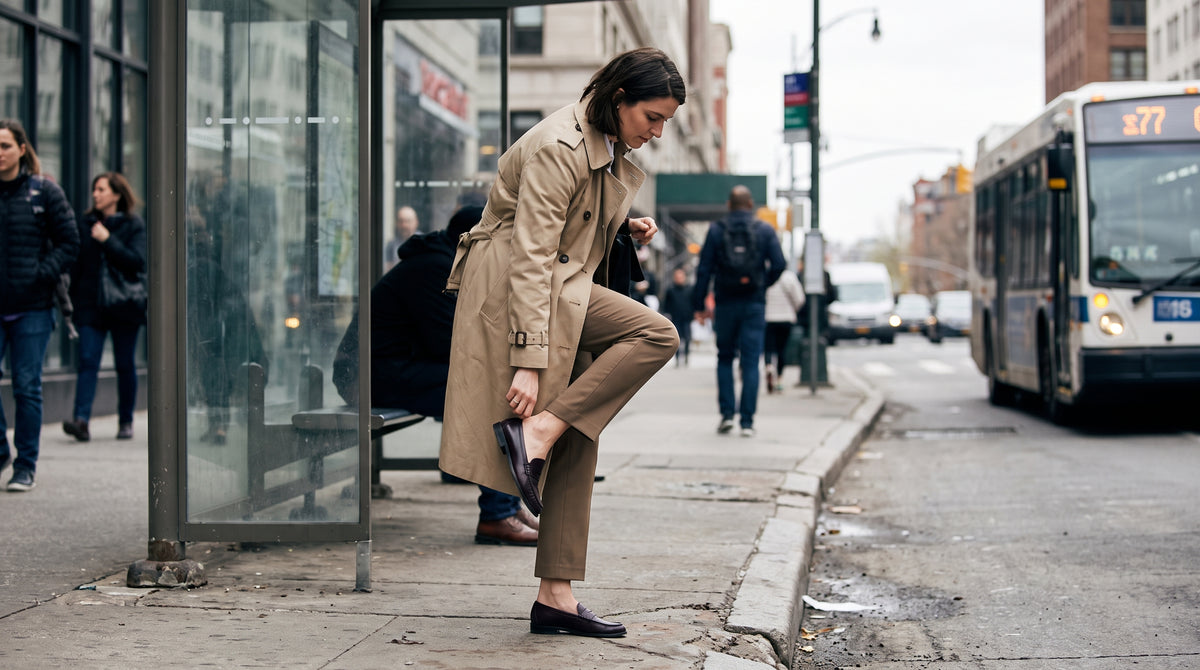 Woman adjusting her loafer at a city bus stop